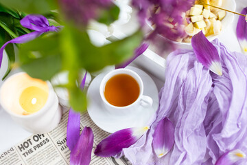 a cup of tea with cakes and a bouquet of flowers on the table