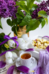 a cup of tea with cakes and a bouquet of flowers on the table