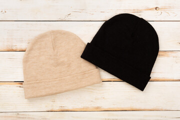 Stylish beanie hat on wooden background, top view