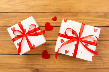 Festive gift boxes with red hearts on wooden background, top view