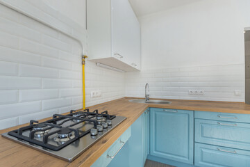 The interior of a simple bright kitchen. Wooden countertop with a hob installed. Gas stove.