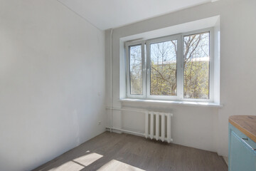 An empty kitchen with light walls, laminate flooring. Unfurnished.