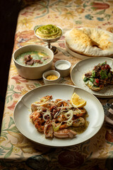 Savoring exquisite flavors at a quaint eatery, multiple dishes showcase a mix of bright ingredients, inviting aromas, and vibrant colors on a floral-tablecloth backdrop