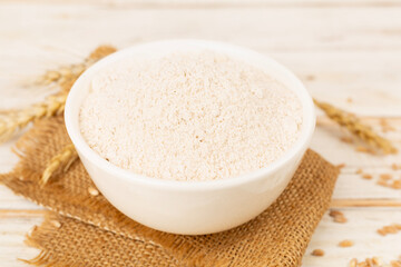 Bowl with spelt flour on wooden table
