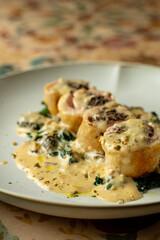 A culinary masterpiece awaits as fluffy rolls rest on a bed of greens, generously drizzled with a rich, creamy sauce