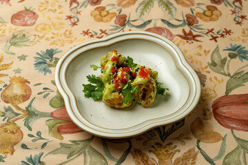 A handcrafted dish featuring vibrant green dumplings garnished with fresh herbs and a sprinkle of spice, beautifully presented on an elegant plate