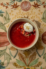 A rich, velvety soup fills a bowl, topped with a dollop of creamy goodness and fresh herbs