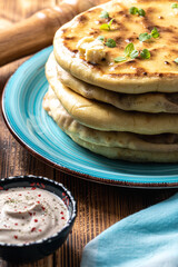 Khychins, traditional Caucasian, Eastern dish. Flatbread stuffed with minced meat with sauce on a turquoise plate with cutlery and a napkin on a wooden table. Vertical photo.
