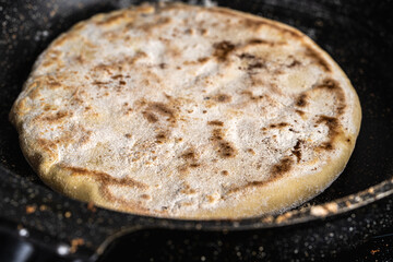 Traditional spanish breakfast potato tortilla. Potatoes in a cast iron frying pan on a rustic wooden background.