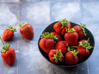Large fresh strawberries in a bowl on a blue background