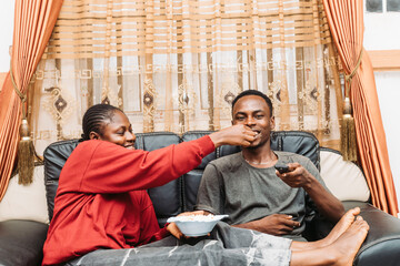 Couple Enjoying A Relaxed Evening Sharing Food And Watching TV Together
