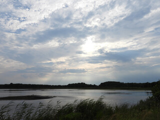 Sunlight beams down from the clouds, highlighting the natural beauty of the wetlands within the...