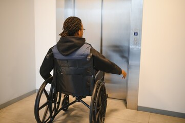 Young man in wheelchair calling the elevator in office building