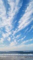 Obraz premium Ocean waves, blue sky, wispy clouds.