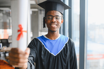 Happy african american graduate showing diploma at university ceremony