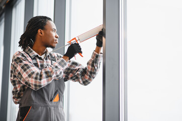 African American Skilled worker sealing window for ventilation repair