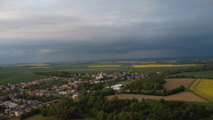 Beautiful Spring Panorama of Hněvošice Village with Blooming Rapeseed and Dramatic Sky
