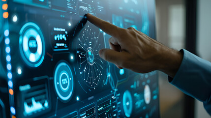 A hand interacts with a blue digital display showing various data visualizations and graphical interfaces