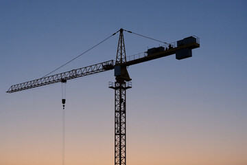Construction crane silhouetted against sunset sky  