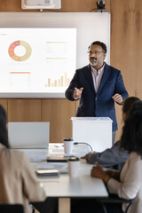 Indian businessman, corporate trainer or business coach dressed in suit stands confidently at...
