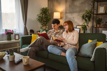 man and woman caucasian adult couple read books at home on sofa bed