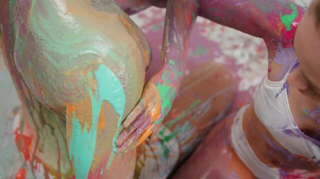 Young couple man and woman doing body art with colourful paints on each other .Man and woman drawing colours paint on their bodies. Body art therapy with many various of paints. Painting on human body