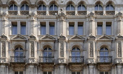 Fototapeta premium A stunning European style of Wrought iron black railings balconies and Classic glass windows in residential tenement building with London victorian architecture. use it as your Wallpaper, Poster.