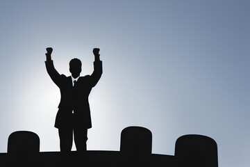 Silhouette of Businessman Celebrating Success with Raised Arms at Sunrise On Top