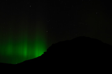 Background of northern lights illuminating a mountain peak at night