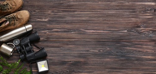 Set of items for trekking on dark wooden background with space for text