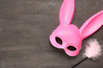 Pink bunny mask with feather stick on grunge background