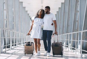 Loving black couple embracing, walking at covered passage in airport