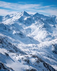 Fototapeta premium Aerial view of snow covered mountains in winter on a sunny day in the Alps with blue sky and clouds