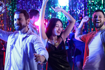 Young Asian woman with her friends dancing at party in night club