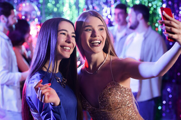Female friends taking selfie at party in night club