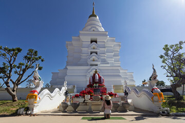 Sacred white chedi at Wat Phra That Muen Hin in Kalasin, Thailand. A revered religious landmark surrounded by nature and cultural heritage.