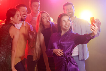Young friends taking selfie at party in night club