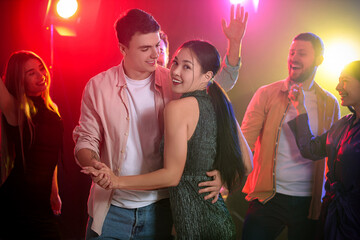 Happy young couple dancing at party in night club