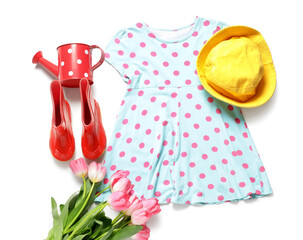 Stylish children's clothes with tulips and watering can on white background