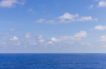 Fototapeta premium Serene Horizon Over Deep Blue Sea With Soft Clouds in Bright Sky