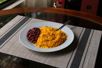 Yellow rice with tuna and red beans on a glass table, typical Costa Rican food