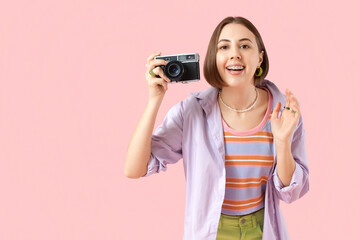 Young woman with dental braces and photo camera on pink background