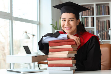 Female graduate with books at table in library
