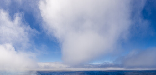 White Clouds Above the Blue Pacific Ocean Under a Clear Sky
