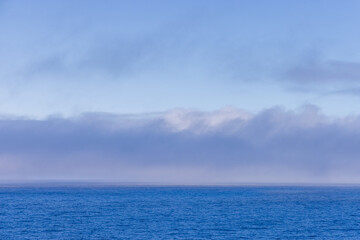 Obraz premium Serene Ocean Horizon with Soft Clouds in the Distance Over Pacific Ocean