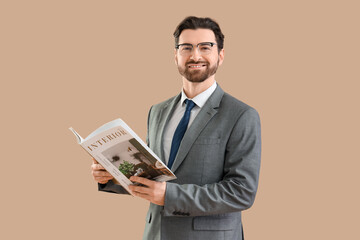Handsome businessman with interior magazine on beige background