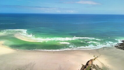 This is a scenic aerial view showcasing a serene beach along with ocean waves crashing gently