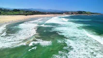Aerial view of a stunning beach with waves and swimmers, capturing leisure and beauty