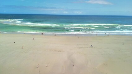 A Stunning Beach Scene with Beautiful Waves and People Joyfully Enjoying the Warm Sun
