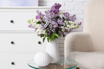 Vase with lilac flowers on table in living room, closeup